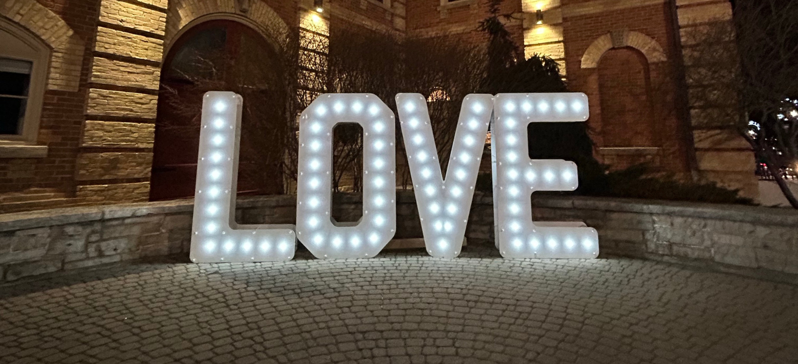 Illuminated letters in front of a historic building spell LOVE.